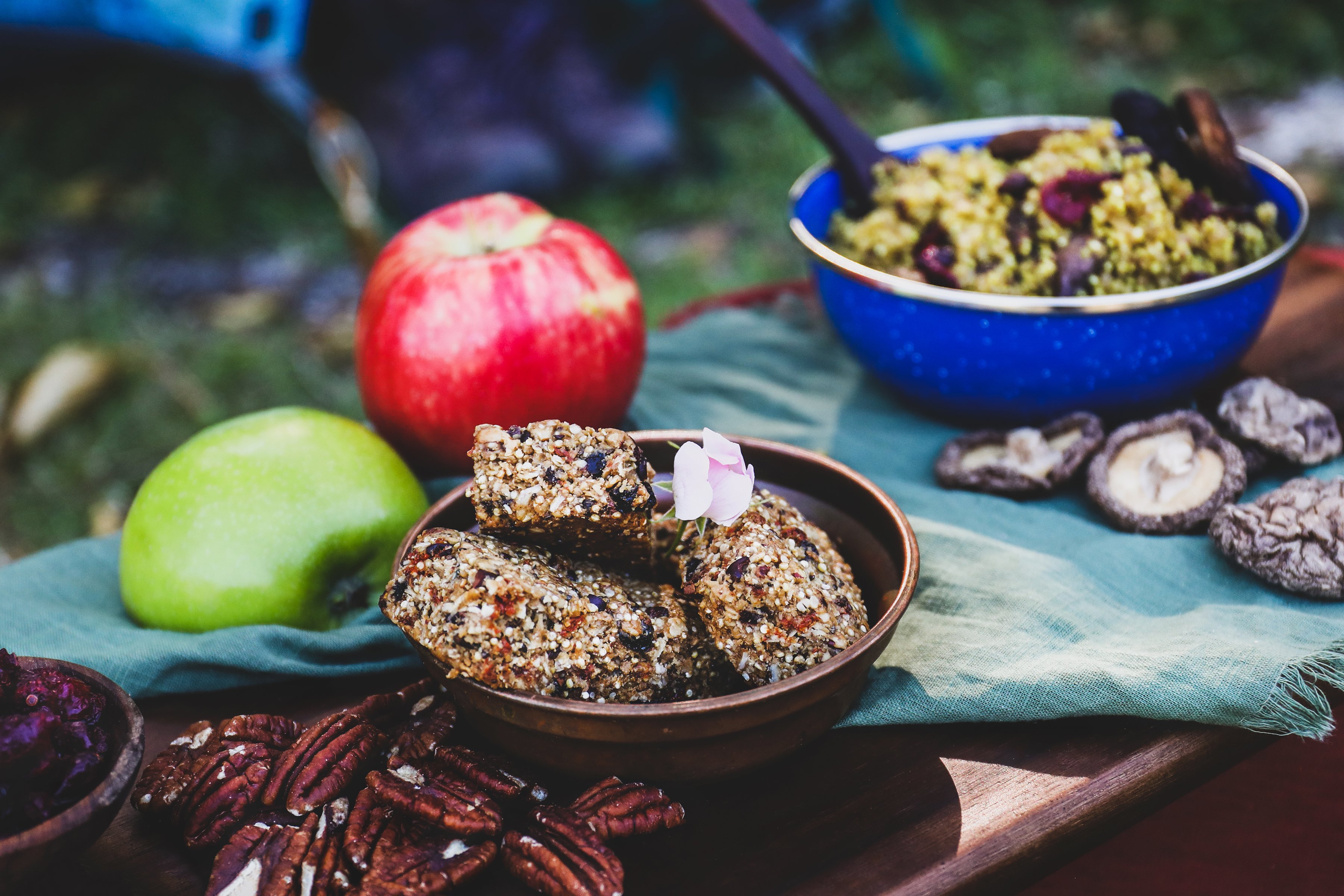 Colorful quinoa bowl with black beans and pumpkin seeds in camping bowl with outdoor gear background