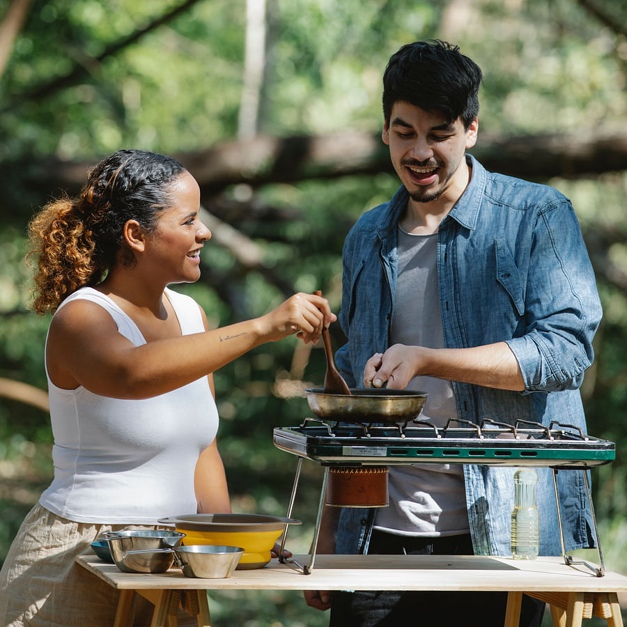 Group of campers joyfully preparing a meal together in a camping setting