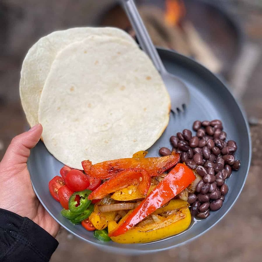 Delicious and colorful campfire grilled veggie tacos served on a camping plate