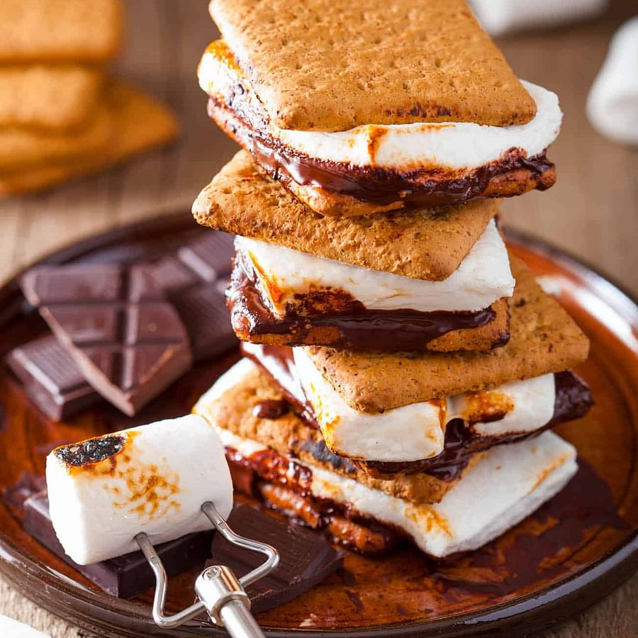 Delicious and mouth-watering Vegan S\'mores served on a rustic wooden table under the starry camping night sky