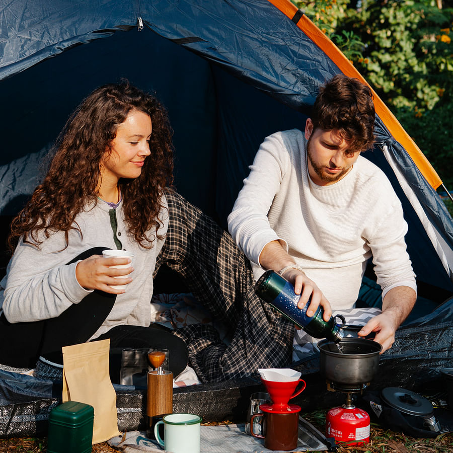 Camper cooking on a portable stove amidst nature